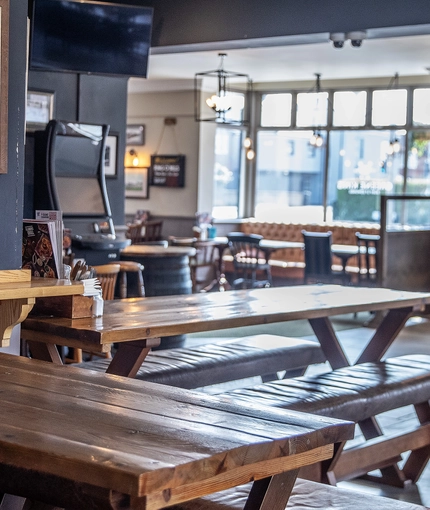 Interior dining area of a pub with TV and a gambling machine.