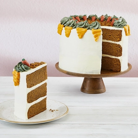 a carrot cake on a stand next to a slice of it on a plate