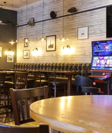 Interior dining area of a pub with a TV and a gambling machine.