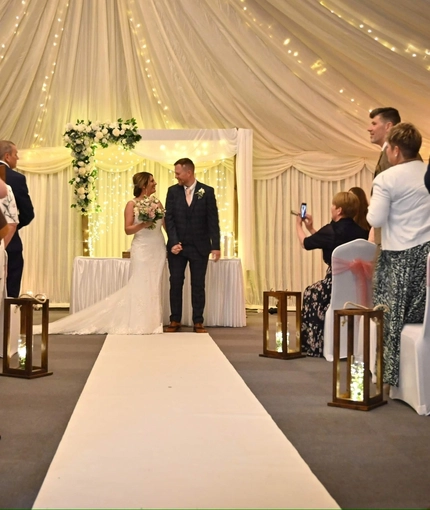 A bride and groom standing at the altar, holding hands.