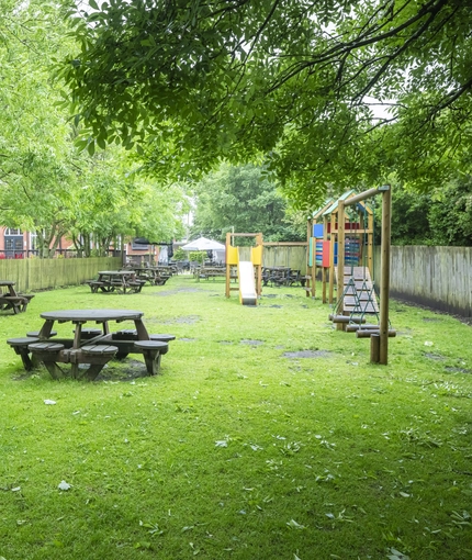 Exterior beer garden and playground of a pub with a seating area.