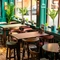 A close up view of the restaurant tables next to the windows inside the Phoenix in Bayswater; with padded seats and bar stools, and potted plants on the window sills.