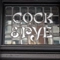 A close up view of a stained glass sign inlaid with the words "Cock & Pye".