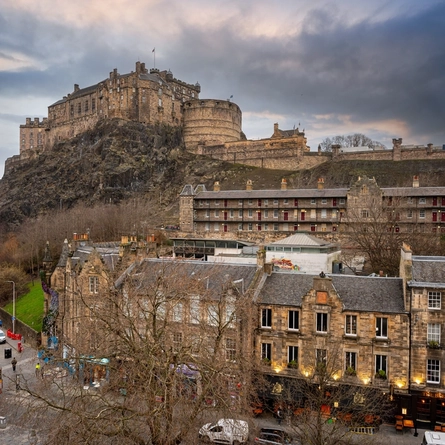 An aerial view of the exterior facade of The Beehive Inn, with a view of Edinburgh Castle on a hill in the background.