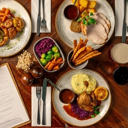 An overhead shot of a range of plated meals on a festive decorated wooden table.
