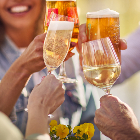An exterior image showing 4 people sat with a selection of alcoholic drinks celebrating with a cheers at a Chef & Brewer venue.