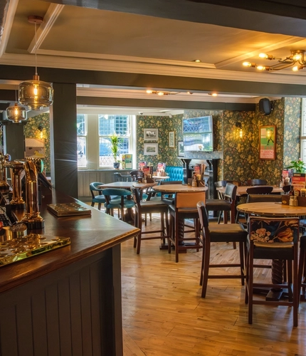 The interior bar and restaurant seating area with TV and fireplace at The Hare & Hounds.