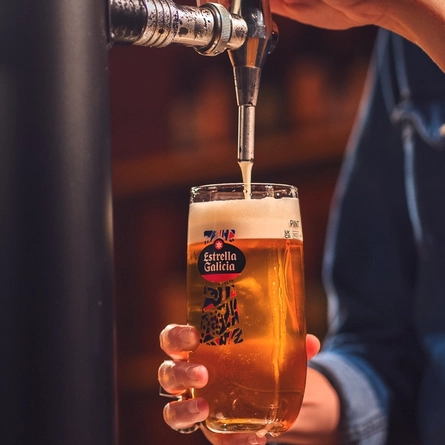 An image of a pint of Estrella Galicia being pouring behind the interior bar.