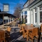 The exterior facade, signage, and seating area of The Horsforth, with wooden picnic tables, shade umbrellas, and string lights overhead.