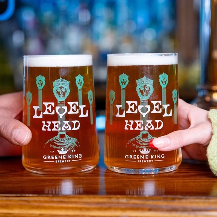 The hands of two people holding a pint of Level Head each on a bar.