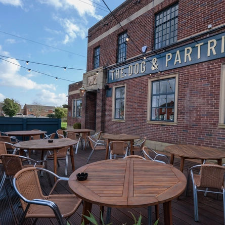 The exterior of the venue with seating are and pub sign at The Dog and Partridge.
