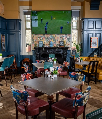 The interior restaurant seating area at The Victoria in Lytham St Annes, with an ornate black fireplace and a TV on the wall.