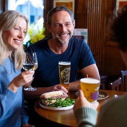 A group of friends sat in the interior restaurant and seating area in a Urban Social venue, enjoying meals off the lunch menu and drinks.