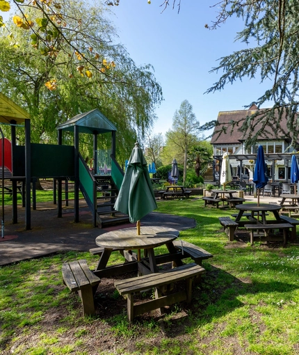 Exterior beer garden of a pub with a play area and a seating area.