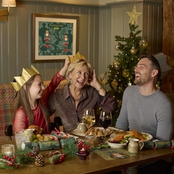 An image showing 2 adults and a child sat within the interior restaurant seating area enjoying Christmas Day dishes at a Chef & Brewer venue.