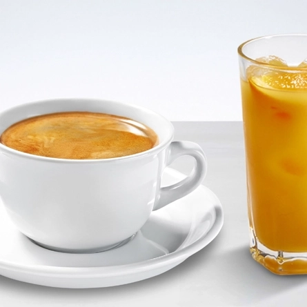 A packshot of a cup of coffee and a glass of fruit juice against a plain background.