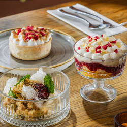 An advertising image showing 3 dessert dishes sat on a table within the interior restaurant seating area at The Four Oaks.