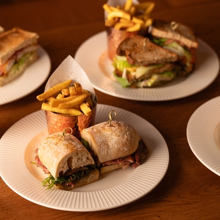 An advertising image featuring a selection of lunch dishes from the AW menu sat on a table available at Crafted & Metro venues.