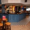 The bar and interior restaurant seating area at the Devonshire Arms, with checkerboard patterned floor, and bar stool seating.