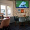 An interior restaurant seating area at the Green Posts, with a TV on the wall, and upholstered seats.