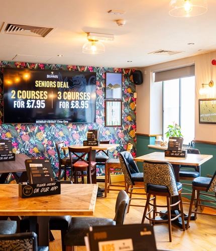 The interior restaurant seating area at the Counting House, with brightly coloured wallpaper, and a TV on the wall.