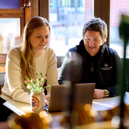 Two Women sat at a table looking at a laptop
