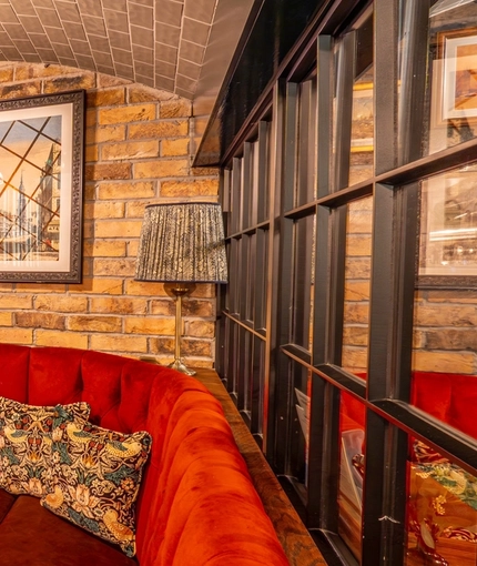 An interior restaurant booth seating area at the Monument, underneath a tiled archway and with framed artwork on the wall.