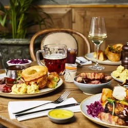 Plates of food and drinks sitting on a wooden table of a pub