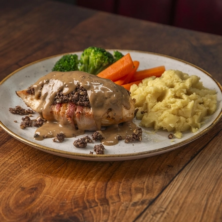 Balmoral chicken served on a plate with vegetables, sitting on a wooden table.