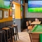 The interior pub gaming area at The Carousel, with a pool table, dartboard, TVs on the walls, stool seating and a restaurant table.