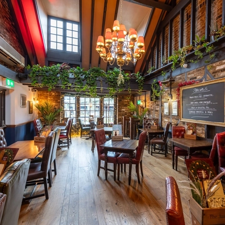 Internal image of the restaurant with a tall ceiling and a large hanging light.