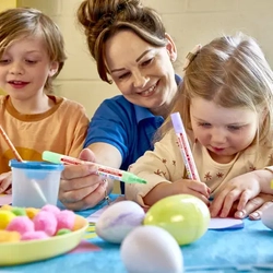 staff member at crafting table doing easter crafts with children