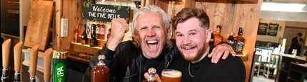 Jimmy Bullard and a GK barman behind a GK bar pumping fists in the air with a pint