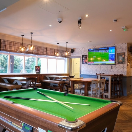 The interior seating area with TV screens, pool table and dartboard at The Ring O' Bells.