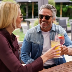 A mixed group of people sat in a beer garden, enjoying cocktails.