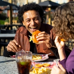 A family enjoying a meal and drinks in the exterior seating area and beer garden from the new Spring/Summer menu at Flaming Grill.