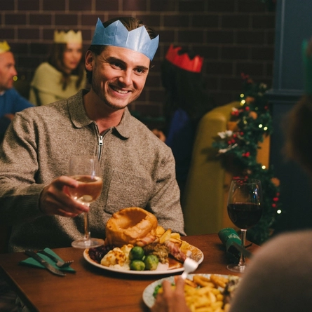 An image of 2 customers sat at a table enjoying festive main dishes and various drinks within the interior restaurant seating area at a Pub & Carvery venue.