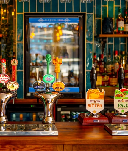 A close up view of the beer taps and golden drinks trays on the bar inside The Windmill Inn.
