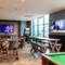 Interior dining area of a pub with a fireplace, a pool table, a gambling machine and a few TVs.