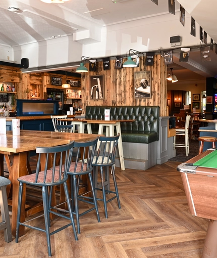 Interior dining area of a pub with a pool table and a bar.