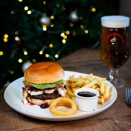 a plate with a sandwich and a glass of beer on a table