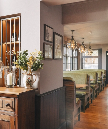 An interior restaurant seating area at Ye Olde Swan, with booth seating, a water station, and framed artwork on the wall.