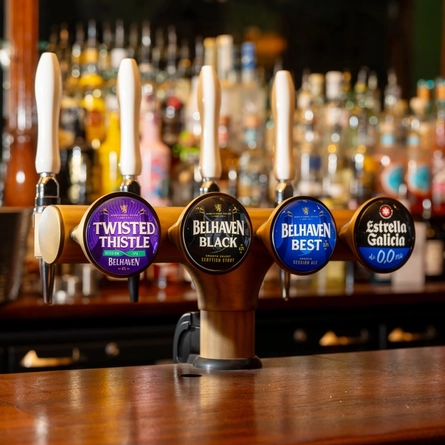 A close up view of the beer taps for Twisted Thistle, Belhaven Black, Belhaven Best, and Estrella Galicia 0.0%, on the bar at The Beehive Inn.