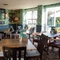 An interior restaurant seating area at the Rudds Arms; with a TV on the wall, and doors leading to the exterior seating area on the deck.