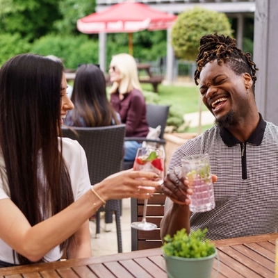 A mixed group of people sat in a beer garden, enjoying cocktails.