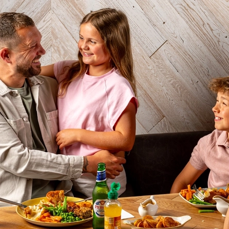 An image of a family enjoying a Sunday Roast and various drinks within the interior restaurant and seating area at a Hungry Horse venue.