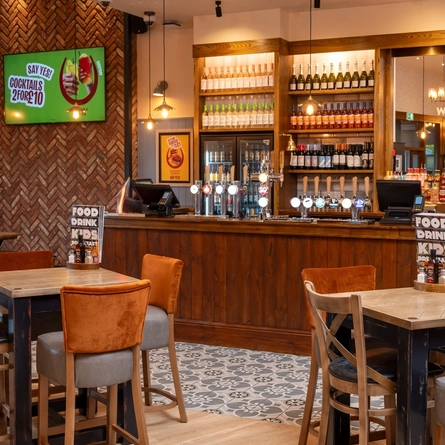 The bar and interior restaurant seating area at The Wrekin Giant, with a TV on the wall, and pub gaming machines.