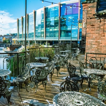 Exterior of the venue with seats overlooking the river with a bridge