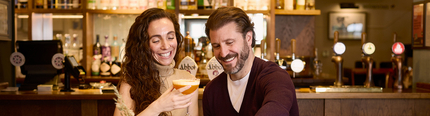 An image of 2 friends sat at a table within the interior restaurant seating area enjoying drinks and a selection of picky bits at a Chef & Brewer venue.