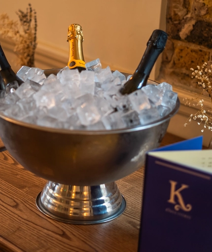 An image of an ice bucket bowl containing various bottle of sparkling white wine sat on a table within the interior of The Kings Stores.